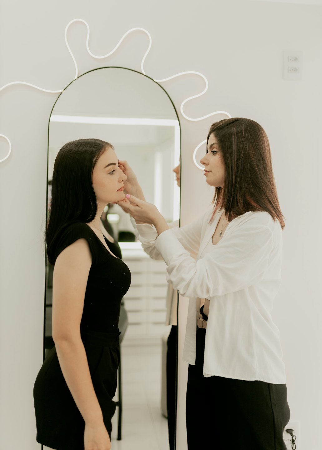 Kozmetička nanáša make-up klientke v modernom salóne.